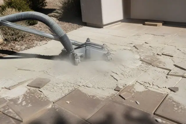Industrial vacuum hose removing ceramic tile debris during a floor demolition in Peoria, AZ.