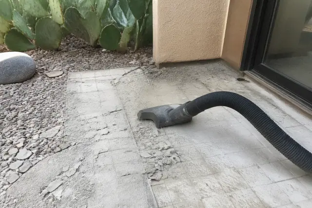Industrial vacuum hose removing shower tile debris at a residential jobsite in Phoenix, AZ.