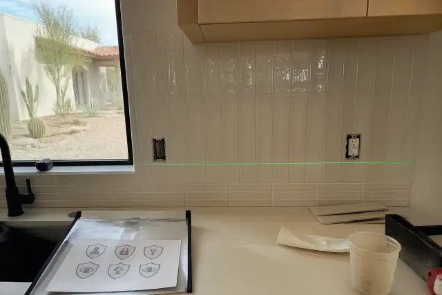 A laser level on a kitchen backsplash showing four-inch and full-height tile options in a Phoenix, AZ home.