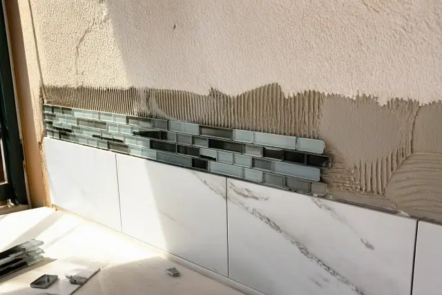 Glass tile accents being installed on a kitchen backsplash wall in Phoenix, AZ.