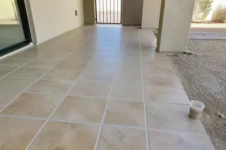 Freshly regrouted floor tiles with a small cup of matching grout in a Phoenix, AZ home.