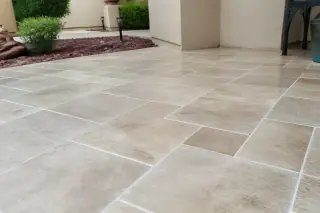 Clean stone floor tiles with uniform grout lines and xeriscape landscaping in a Phoenix, AZ home.