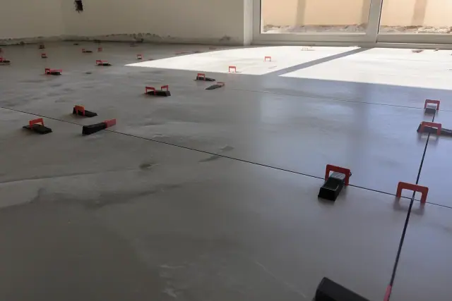 Leveling clips and wedges installed between porcelain floor tiles at a job site in Phoenix, AZ.
