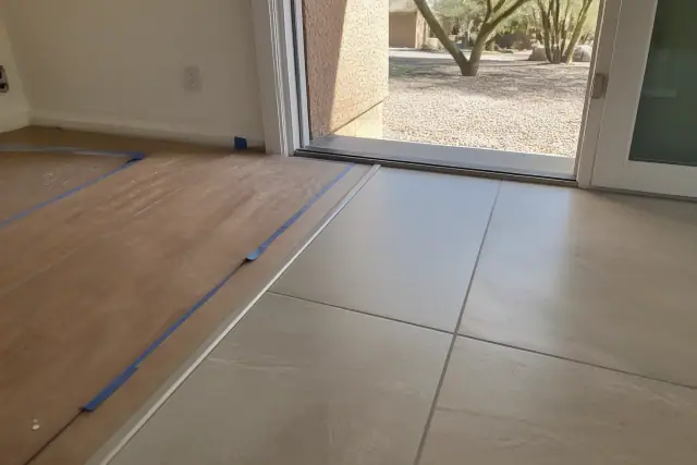 Transition strip connecting tile to wood flooring in a Phoenix, AZ home with outdoor desert landscaping visible.
