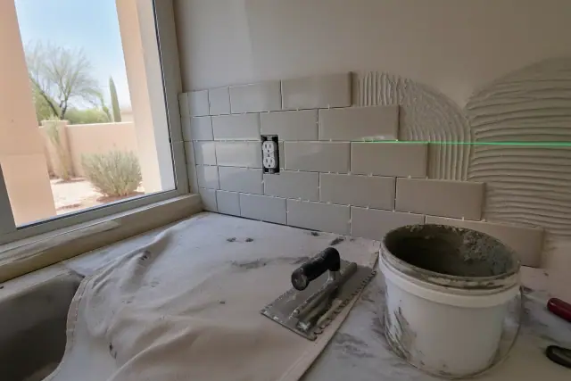 Kitchen tile backsplash installation with a laser level in a Peoria, AZ home.