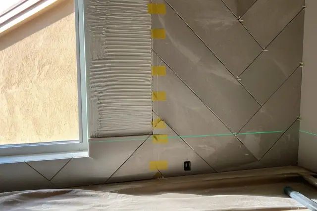 Laser level beam projected across a tile backsplash under construction in a kitchen in Gilbert, AZ.