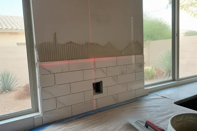 Tile backsplash installation with a laser level in a Chandler, AZ kitchen.