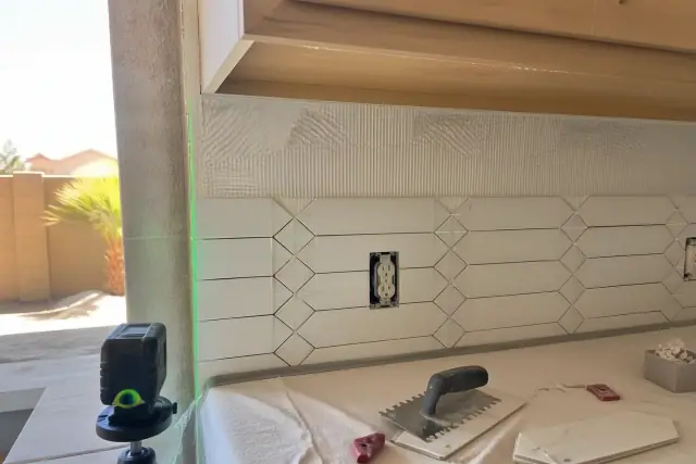 Contractor photo of a tile backsplash installation with a laser level beam in a Phoenix, AZ kitchen.