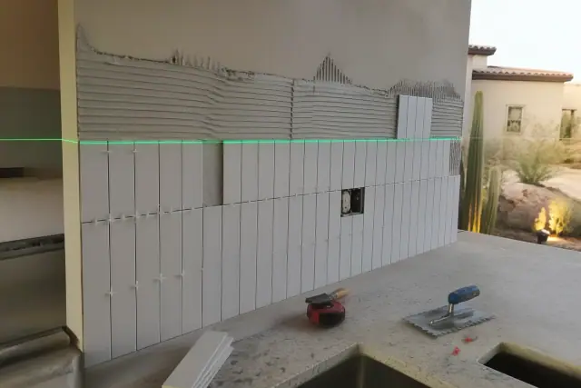 Kitchen backsplash installation with a laser level and mortar in progress at a home in Scottsdale, AZ.