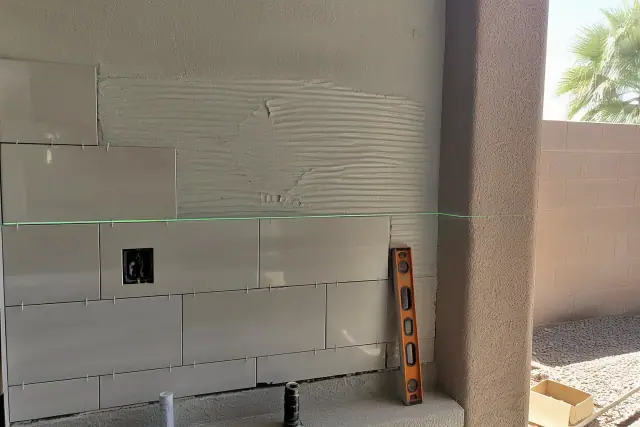 Laser level beam on a kitchen backsplash tile repair project in a Phoenix, AZ home.