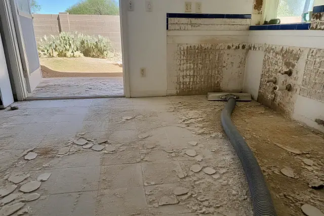 Industrial vacuum hose removing kitchen tile during a renovation project in Phoenix, AZ.