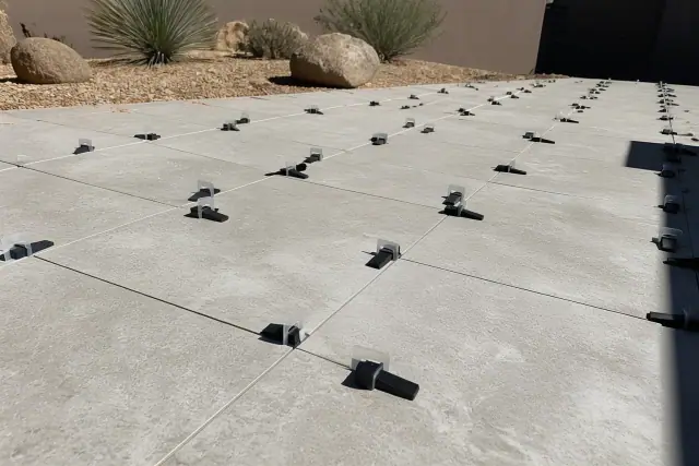 Plastic leveling clips and wedges installed between large outdoor tiles on a patio project in Phoenix, AZ.