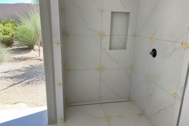 Large-format tiles being installed with leveling spacers in a shower in Phoenix, AZ.