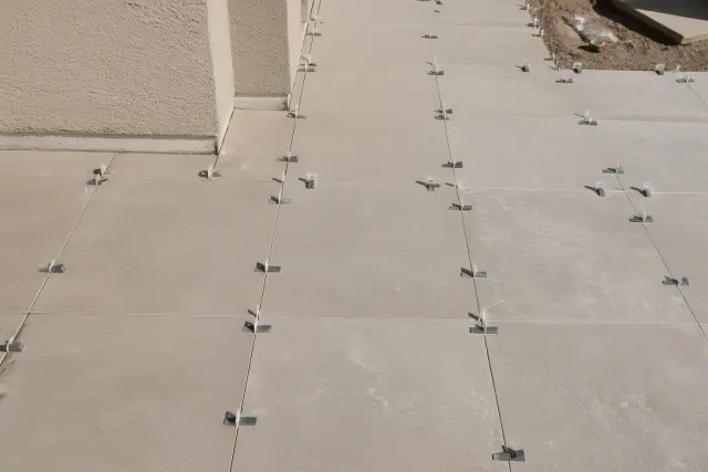Plastic leveling clips and wedges installed between natural stone tiles at a construction site in Phoenix, AZ.