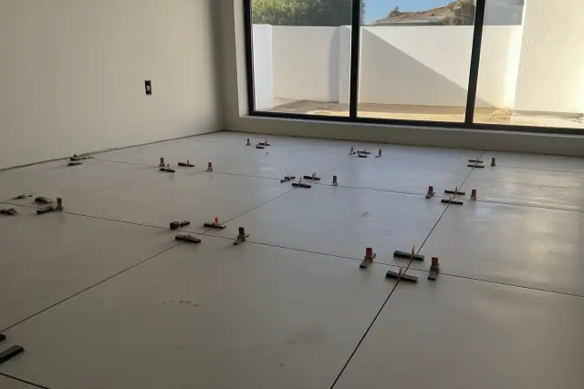 Large format tile installation with leveling clips and wedges on a residential job site in Phoenix, AZ.