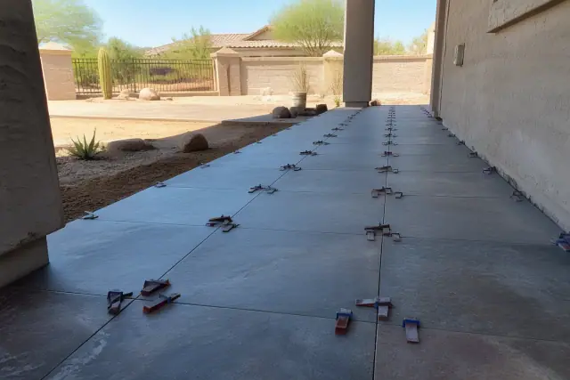 Large format tile installation with leveling clips and wedges on a residential job site in Goodyear, AZ.