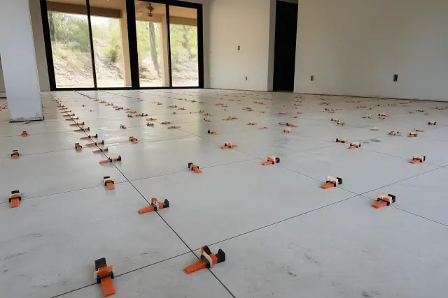 Plastic leveling clips and wedges installed between large-format floor tiles at a residential jobsite in Scottsdale, AZ.