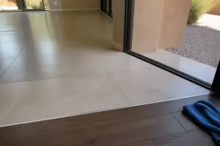 Rectified porcelain tile transition to wood flooring in a Phoenix, AZ home with xeriscaping visible outside.