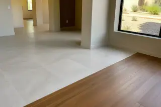 Wide view of a tile to wood floor transition in a sunlit Phoenix, AZ home with desert landscaping visible through a window.