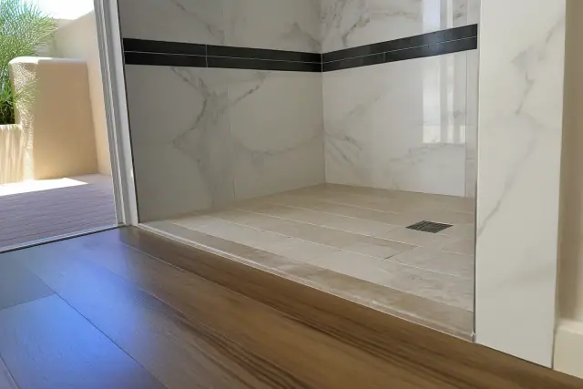 Marble, slate, and travertine tile installation with a transition strip to a wood floor in a Phoenix, AZ bathroom.