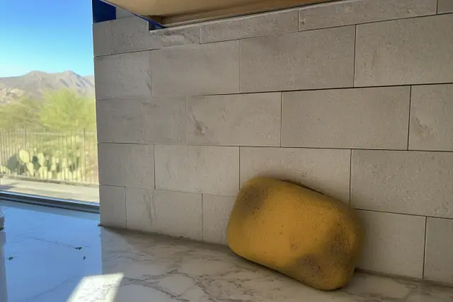 Damp sponge wiping excess mortar from newly installed stone kitchen backsplash tiles at a residential job in Phoenix, AZ.