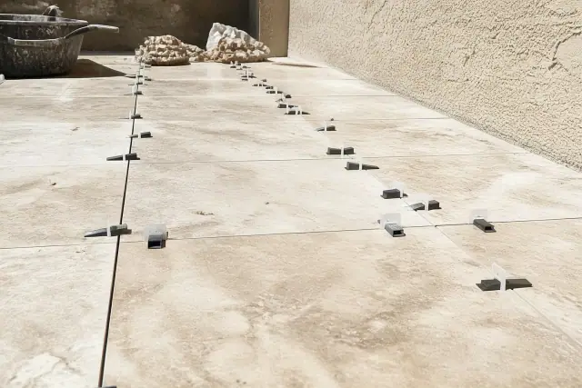 Natural stone tiles being installed with leveling clips and wedges on a construction site in Phoenix, AZ.