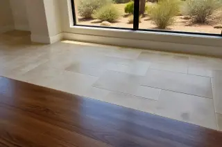 Natural stone tiles with clean grout lines beside wood flooring in a Phoenix, AZ home with desert plants outside.