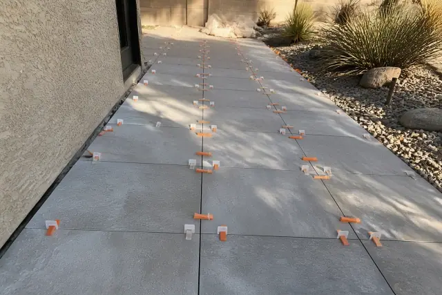 Outdoor tile installation with leveling clips and wedges on a patio in Glendale, AZ.