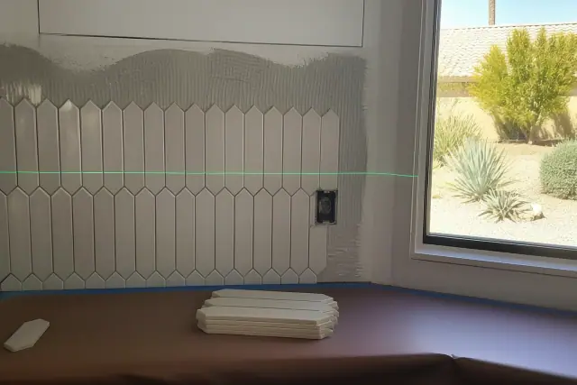 Laser level beam on a kitchen backsplash tile installation in Phoenix, AZ.