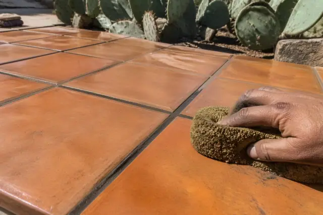 A sponge wiping mortar from between newly installed Saltillo patio tiles at a jobsite in Phoenix, AZ.