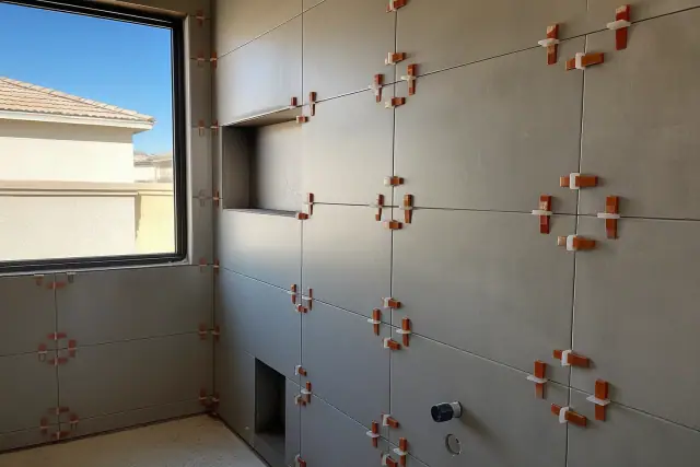Large format tiles with leveling clips and wedges installed in a bathroom renovation in Phoenix, AZ.