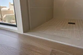 Stone tile shower transition strip connecting to a wood floor in a Phoenix, AZ home.