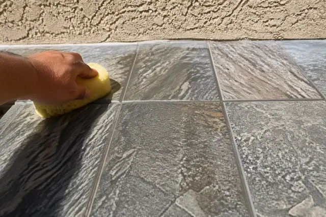 Damp sponge wiping excess mortar from new slate tile installation on a Phoenix, AZ jobsite.