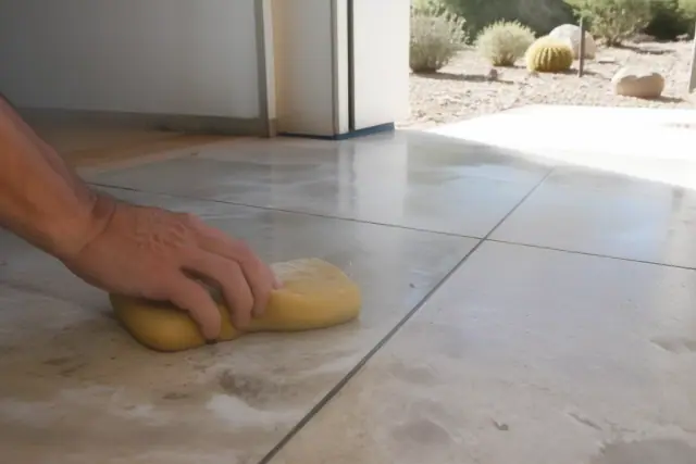 A damp sponge wiping mortar from new stone tile grout lines at a job site in Scottsdale, AZ.