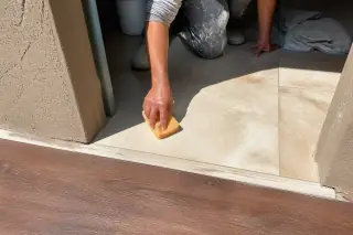Worker using a sponge to clean a tile and wood floor transition in a Phoenix, AZ home.