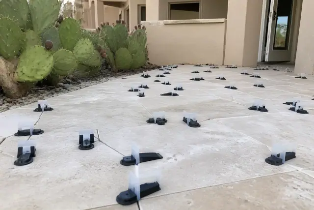 Travertine tiles with leveling clips and wedges on a jobsite in Phoenix, AZ with desert cacti in the background.