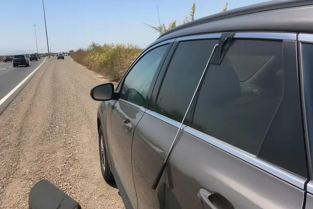 A specialized long-reach lockout tool used on a car parked on a gravel roadside in Phoenix, AZ.