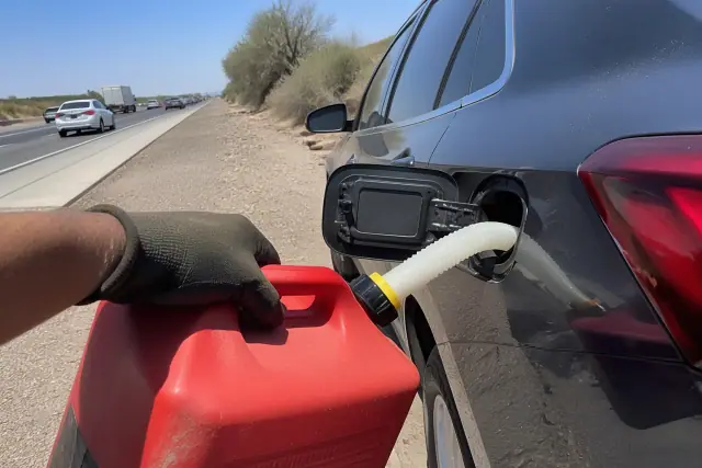 A technician refueling a disabled vehicle on a highway shoulder in Phoenix, AZ.