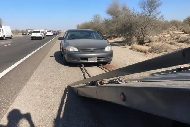A tow truck prepares to load a disabled vehicle on a highway shoulder in Phoenix, AZ.