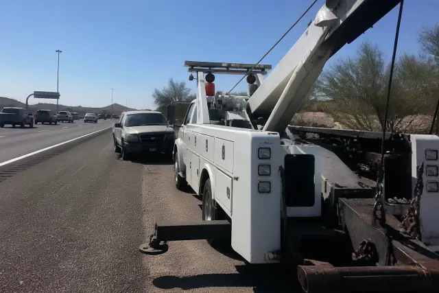 Heavy-duty tow truck performing a recovery on a disabled vehicle on a highway shoulder in Phoenix, AZ.