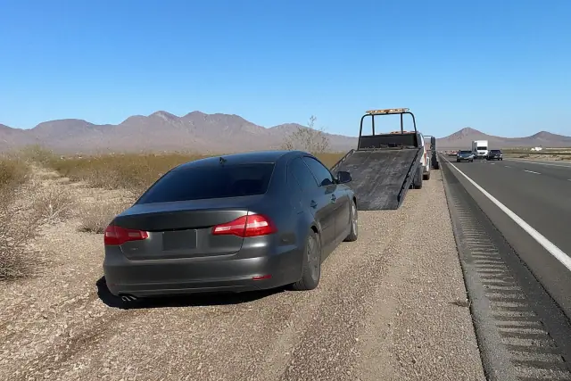 Disabled vehicle parked on a gravel shoulder near a multi-lane highway in Tempe, AZ.