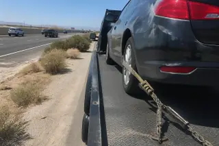 Heavy-duty wheel straps and chain tensioners securing a car on a tow truck in Phoenix, AZ.
