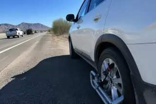 Wheel-lock alignment on a vehicle parked on a gravel highway shoulder with desert mountains in Phoenix, AZ.