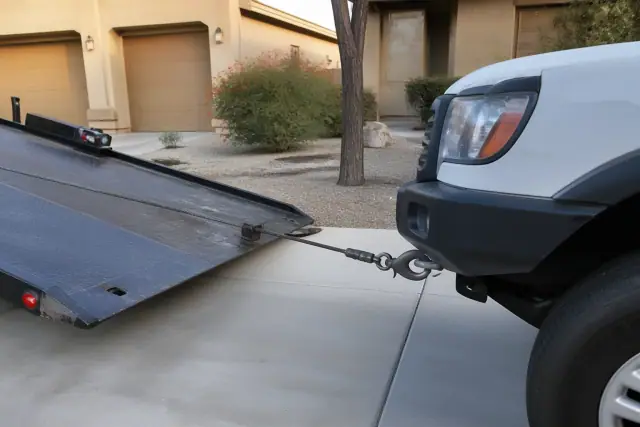 A vehicle being winched onto a tow truck bed in a residential driveway in Phoenix, AZ.