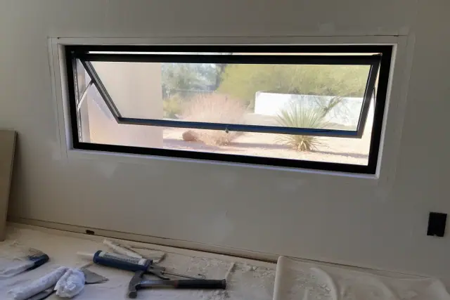 Aluminum awning window frame installation on a stucco wall at a jobsite in Phoenix, AZ.