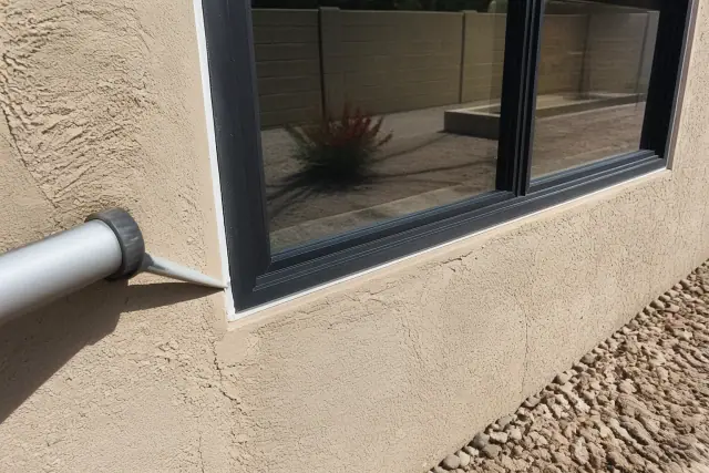 Caulking the frame of a new aluminum window on a stucco wall at a jobsite in Chandler, AZ.