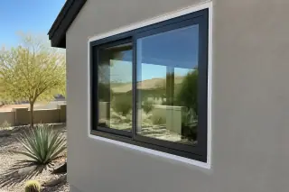 Close-up of fresh caulk along an aluminum window frame on a stucco home in Phoenix, AZ.
