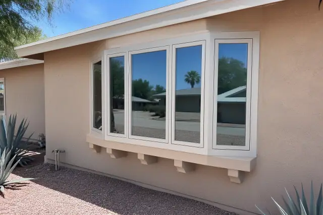 Finished five-panel bow window with support brackets on a stucco home in Tempe, AZ, surrounded by gravel xeriscape.