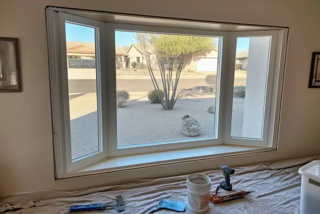 Bay and bow window installation in a Phoenix, AZ residential living room with tools and materials on a drop cloth.