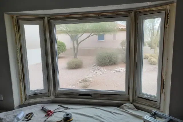 Interior view of a bay window frame installation in a Phoenix, AZ home with tools and materials on a drop cloth.